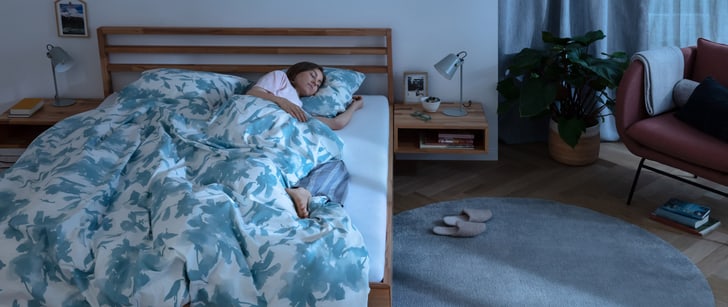 Une femme dort dans un lit en bois, sous une couverture.