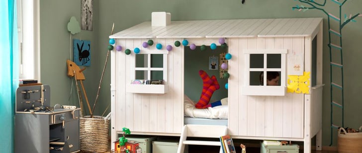 Chambre d’enfant avec cuisine pour jouer. Une fillette est sur un lit qui ressemble à une maison.