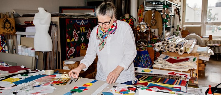 Personne travaillant dans un atelier créatif avec des tissus et des motifs colorés.
