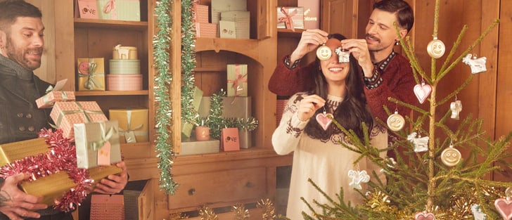 Des personnes décorent un sapin de Noël et tiennent des cadeaux.