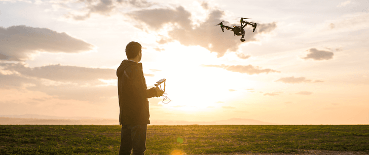 Un jeune homme fait voler son drone au coucher du soleil