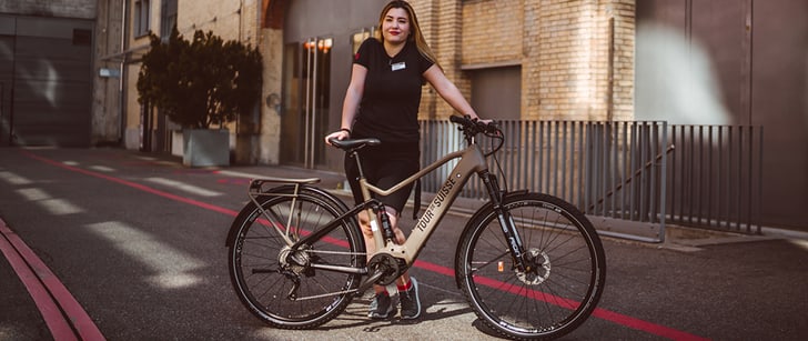Une vendeuse Bike World présente un vélo électrique dans la rue.