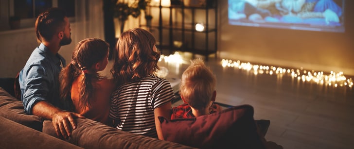 Una famiglia di quattro persone siede sul divano e guarda insieme un film