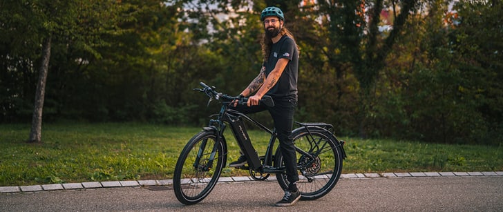 Un vendeur Bike World avec un casque est assis sur un vélo électrique FLYER.