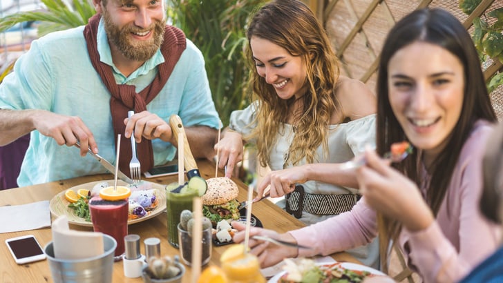 Lachende Freunde sitzen am Tisch und essen den neusten Foodtrend