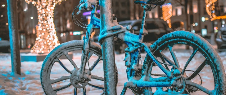 Una bici ricoperta di neve è incatenata a un lampione e il lucchetto è congelato