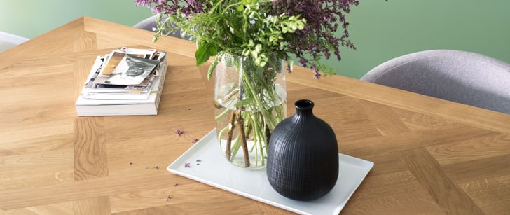 Blumenvase auf einem Tablett steht auf einem Holztisch
