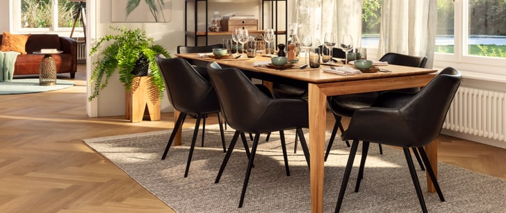 Table de salle à manger en bois avec chaises habillées de cuir. La table est mise.