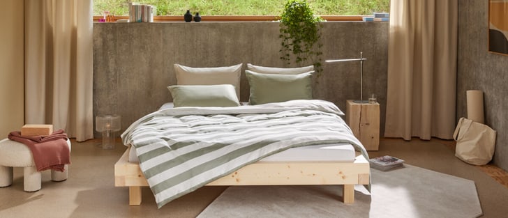 Chambre moderne avec un lit en bois et du linge de lit rayé.