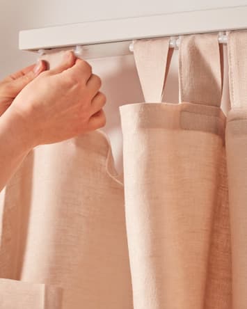 Des mains accrochent un rideau à une tringle.