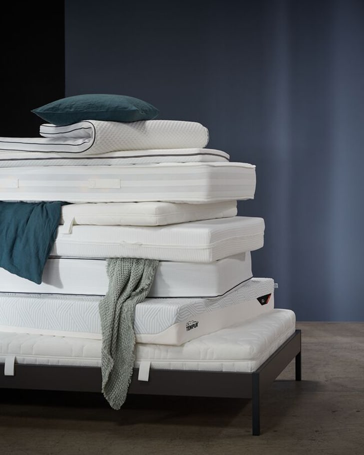 Pile de matelas et de linge de lit sur un cadre de lit, avec un oreiller et une couverture.