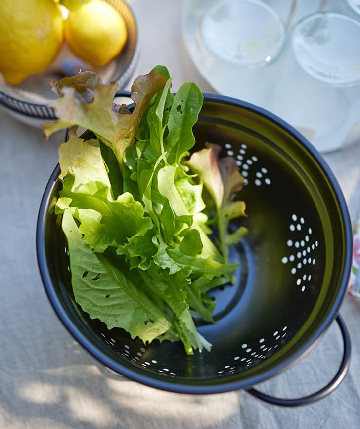 Insalata fresca in un colino nero su un tavolo.