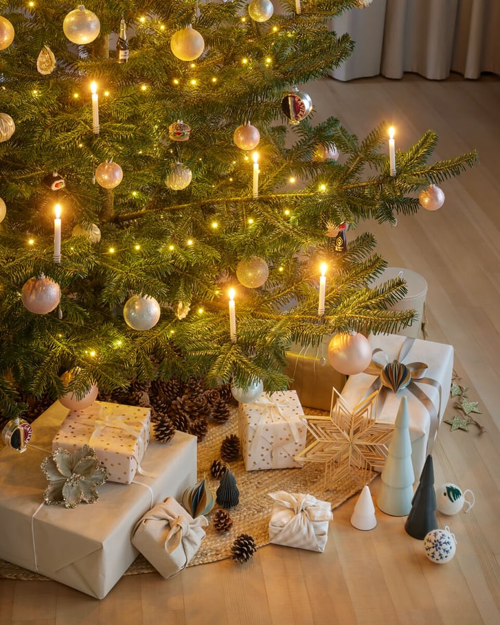 Ein Weihnachtsbaum mit Lichtern und Kugeln, umgeben von Geschenken.