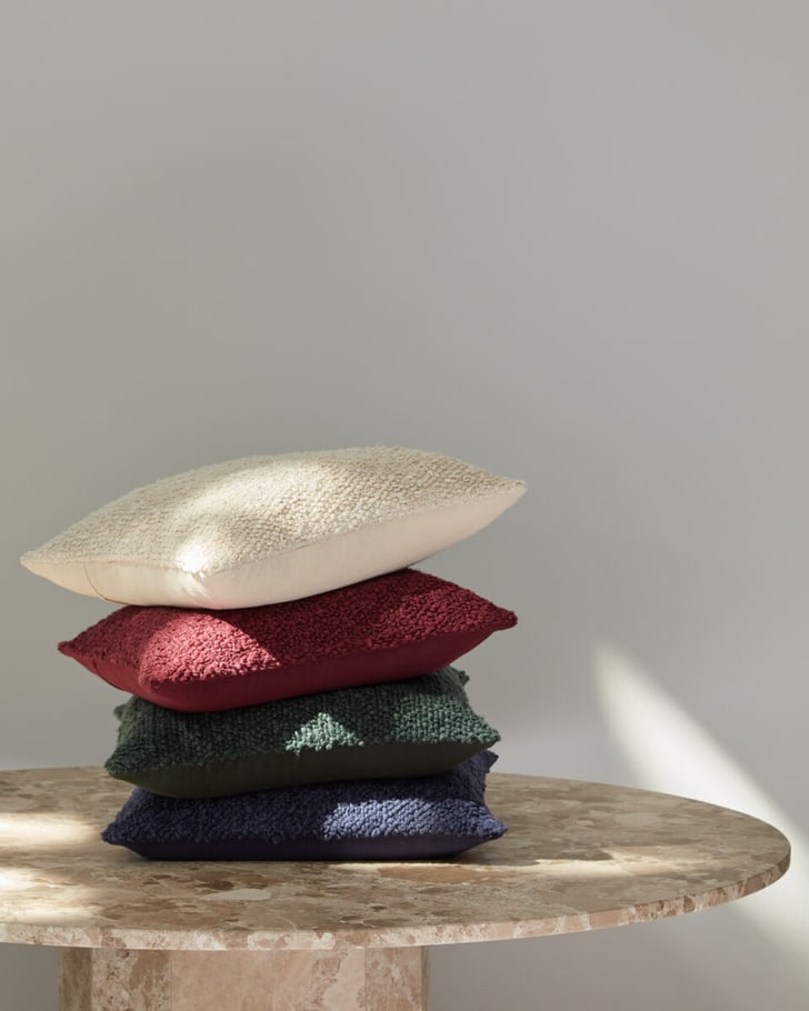 Une pile de coussins en bouclette sur une table, doux et accueillants, arrangés dans des couleurs douces.  