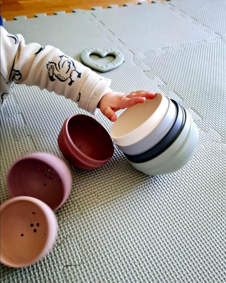 Une main d&apos;enfant attrape des gobelets empilables sur un tapis de jeu.