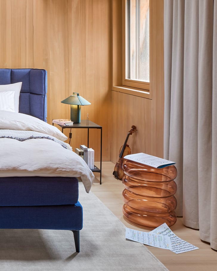 Chambre à coucher confortable avec un lit bleu et une table de nuit en verre coloré.  