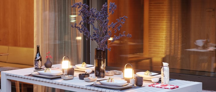 Eleganter, gedeckter Tisch im Freien mit moderner Dekoration und stimmungsvoller Beleuchtung.