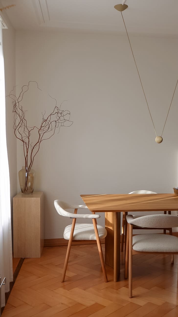Salle à manger minimaliste avec des meubles en bois et des branches décoratives.