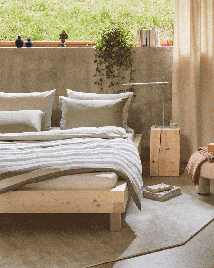 Chambre confortable avec lit en bois, literie verte et plantes à la fenêtre.