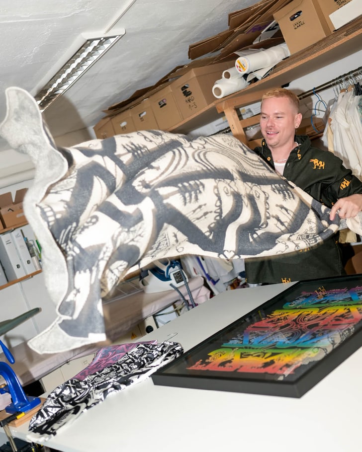 Julian Zigerli in seinem Studio, während er ein großes bedrucktes Tuch bewegt.