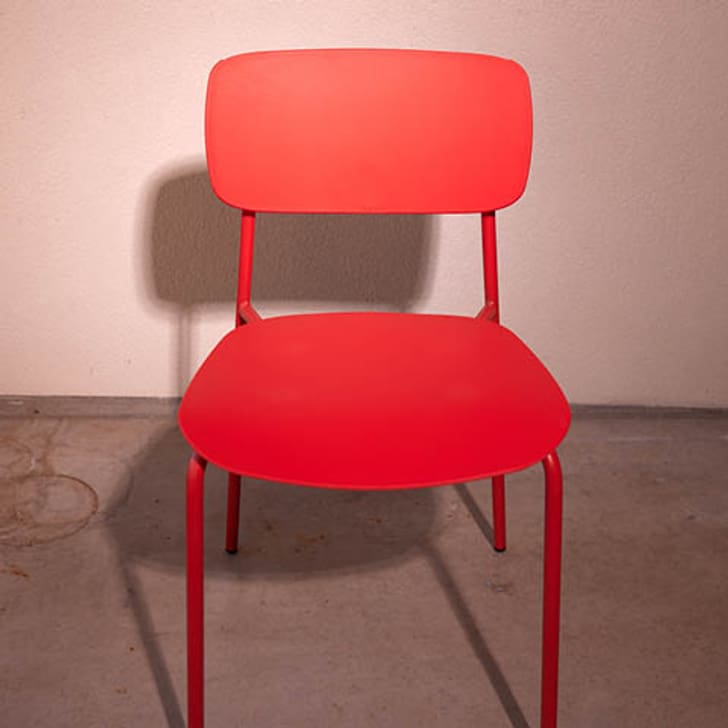 Ein roter Stuhl COLORE steht auf einem Betonboden.