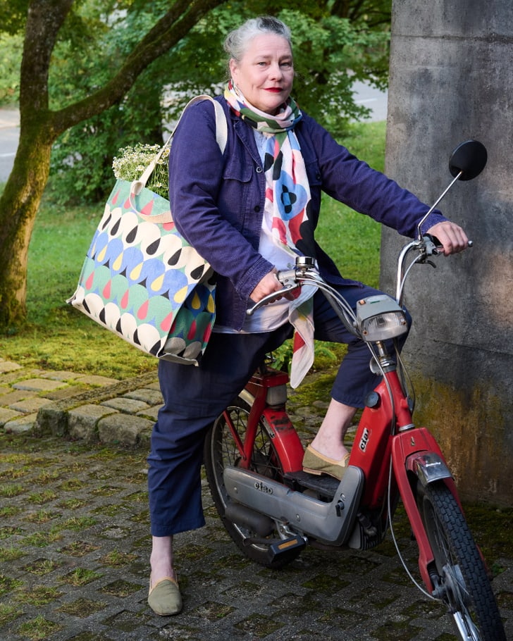 Personne sur un vélomoteur rouge avec un sac coloré et une écharpe.