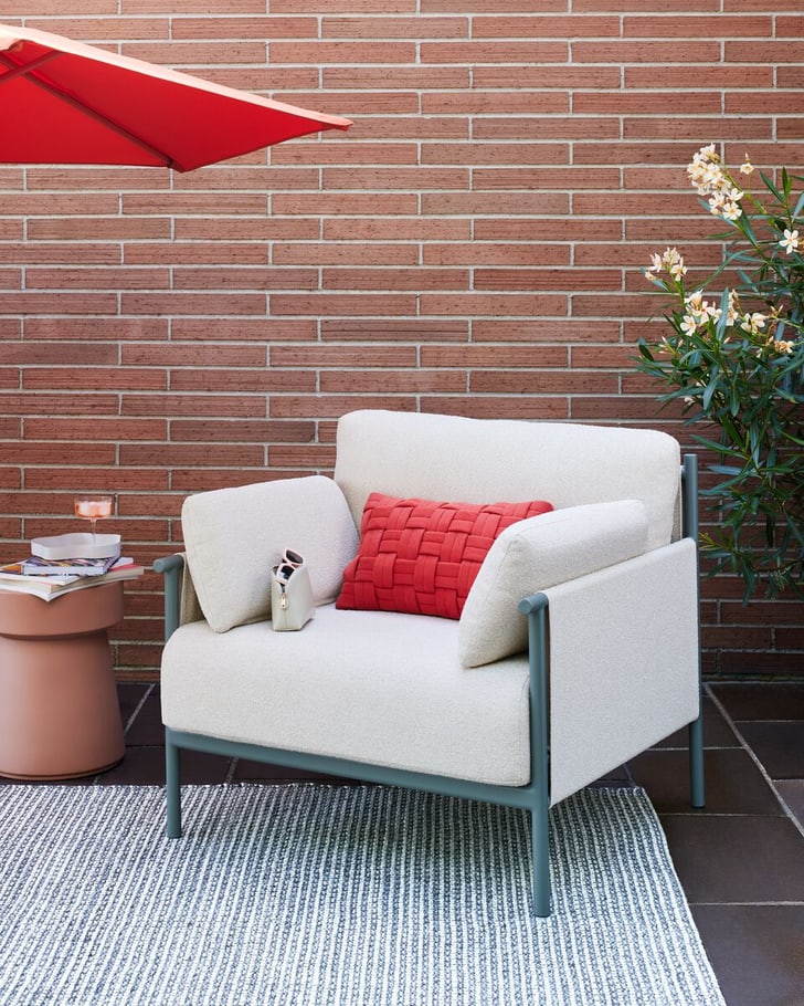 Fauteuil confortable sur la terrasse avec coussin rouge et table d'appoint sous un parasol.