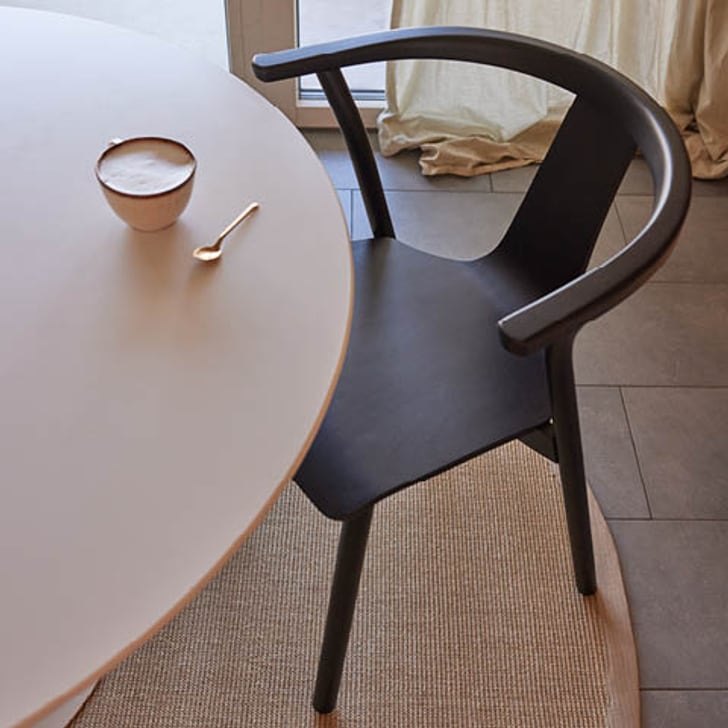 Schwarzer Stuhl NELLO neben einem Tisch mit einer Tasse Kaffee.