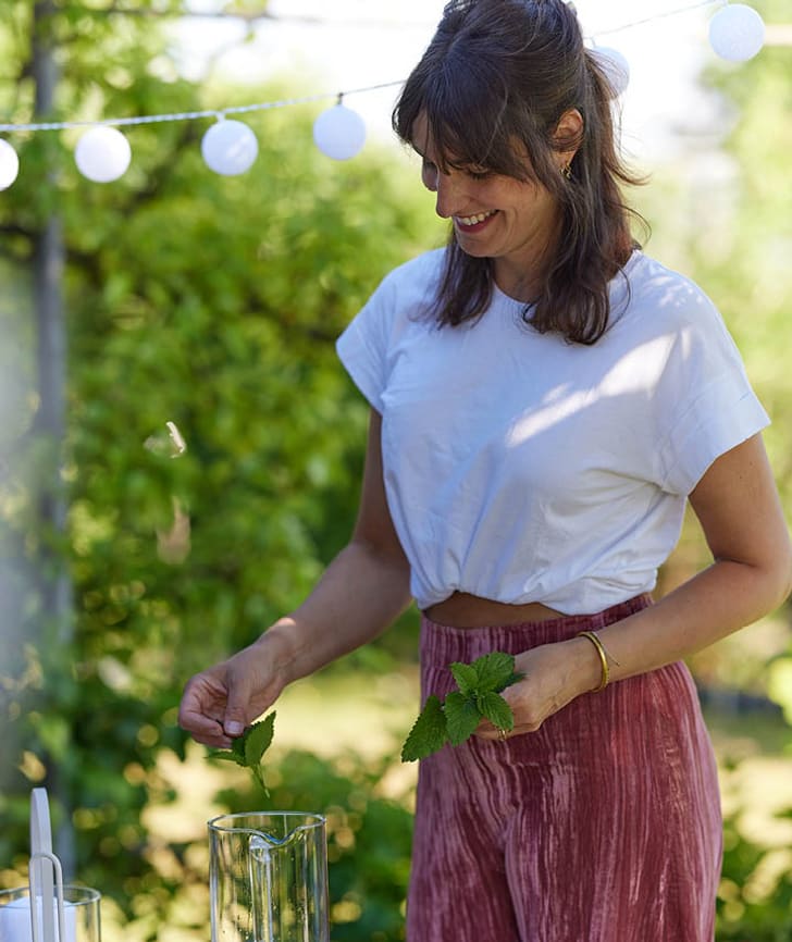 Donna che prepara bevande fresche con menta in giardino.