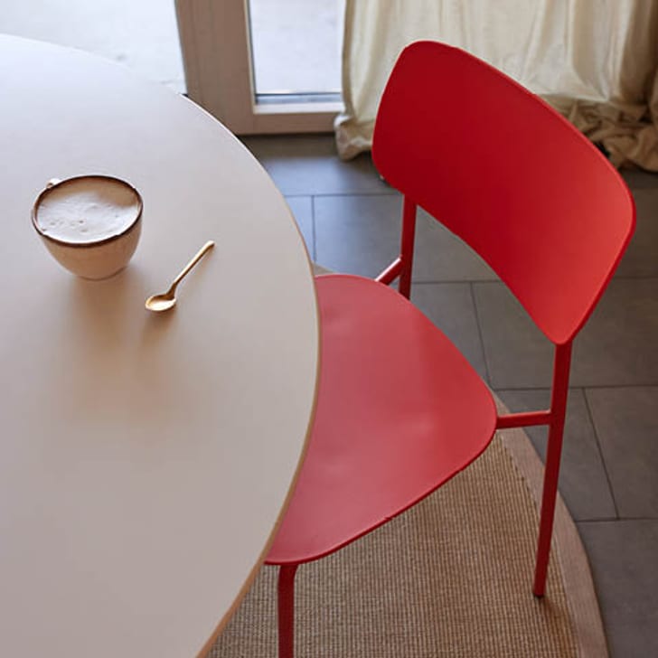 Roter Stuhl COLORE neben einem Tisch mit einer Tasse Kaffee.