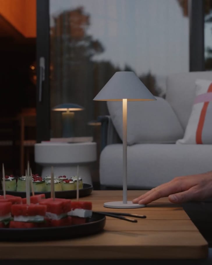 Scène de table chaleureuse avec lampe moderne, amuse-bouches et ambiance conviviale.