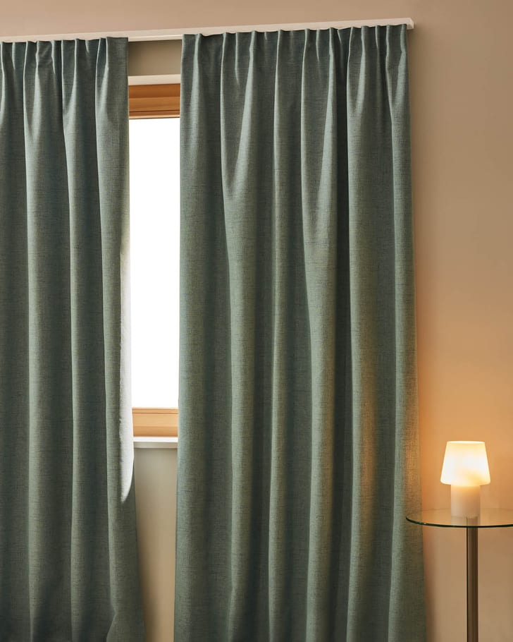Rideau occultant devant une fenêtre avec une lampe de table à côté.
