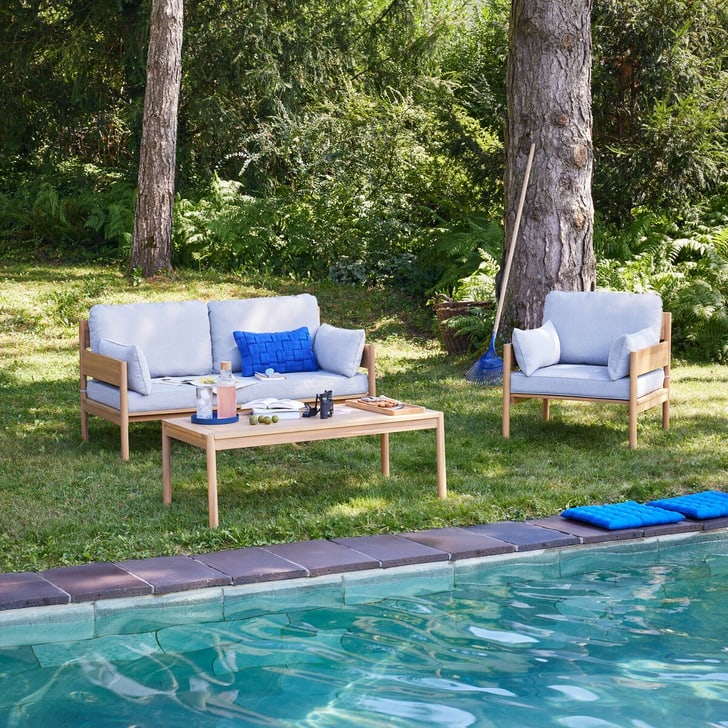 Ensemble de sièges en bois avec coussins bleus au bord de la piscine dans le jardin.