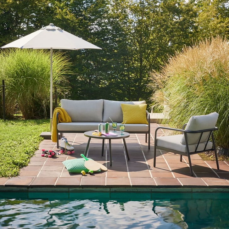 Scène de jardin confortable avec lounge, table et parasol, parfaite pour un après-midi relaxant en plein air.