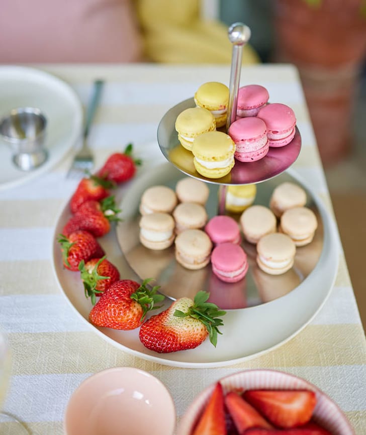 Bunte Macarons auf einer Etagere und frische Erdbeeren auf einem Teller.