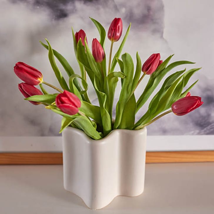 Rote Tulpen in der weissen, wellenförmigen Vase NOLA vor einem wolkigen Hintergrund.