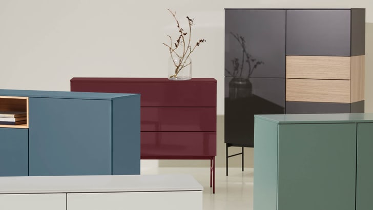 Sammlung von Kommoden in verschiedenen Farben und Designs, dekoriert mit einem Zweig in einer Vase.
