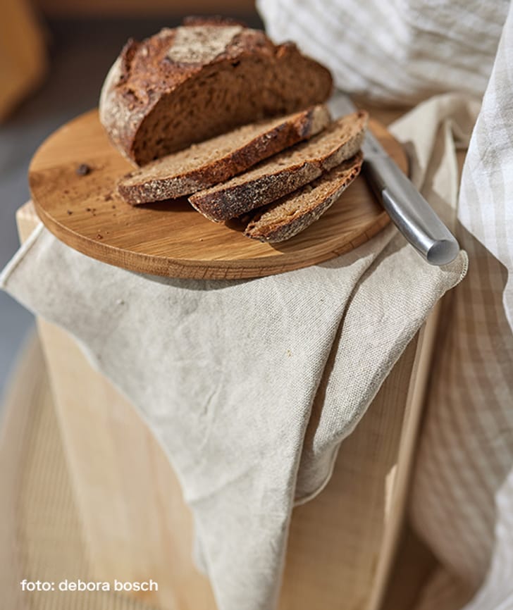 Geschnittenes Brot auf einem Holzbrett mit einem Messer.