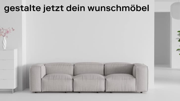 Ein modernes graues Sofa vor einer weißen Wand mit dem Text &quot;gestalte jetzt dein Wunschmöbel&quot;.