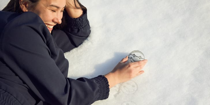 Person liegt im Schnee und hält eine Smiley-Ausstechform.