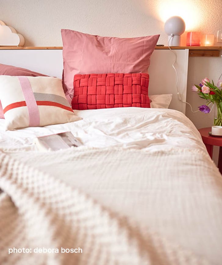 Un lit confortable avec des coussins colorés et une lampe de chevet.