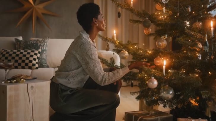 Personne décorant un sapin de Noël dans le salon.