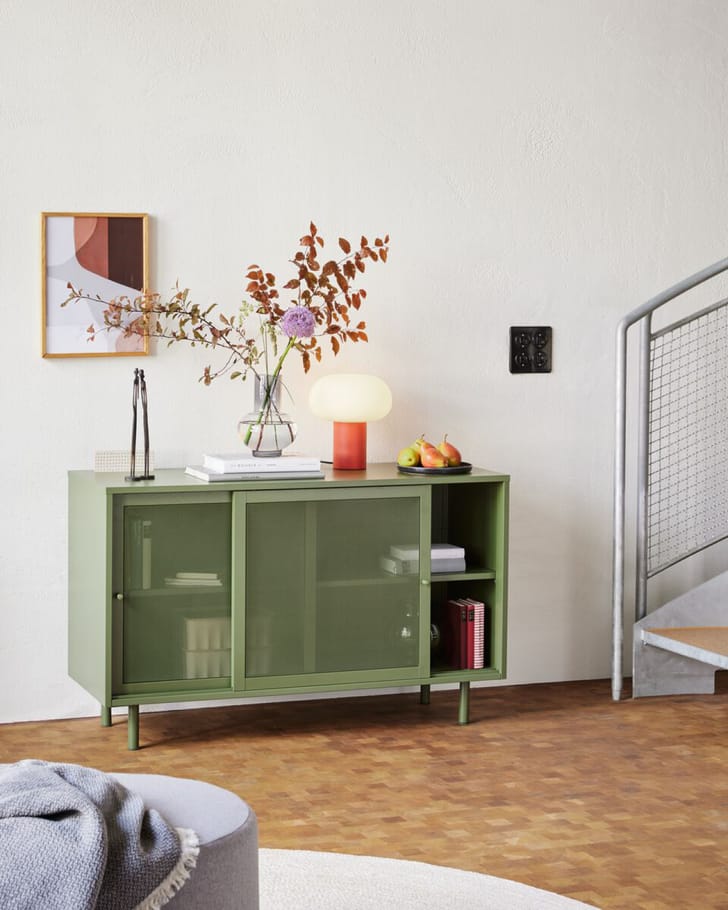 Stilvolles grünes Sideboard mit einer Vase, die den Raum harmonisch ergänzt.  