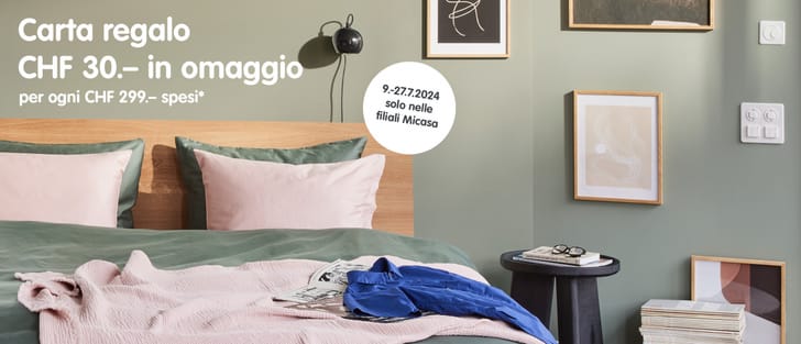 ﻿Scena della camera da letto con un grande letto matrimoniale, in cui domina il colore verde salvia, completato da singoli accenti in rosa (cuscini) o blu reale (coperta).
