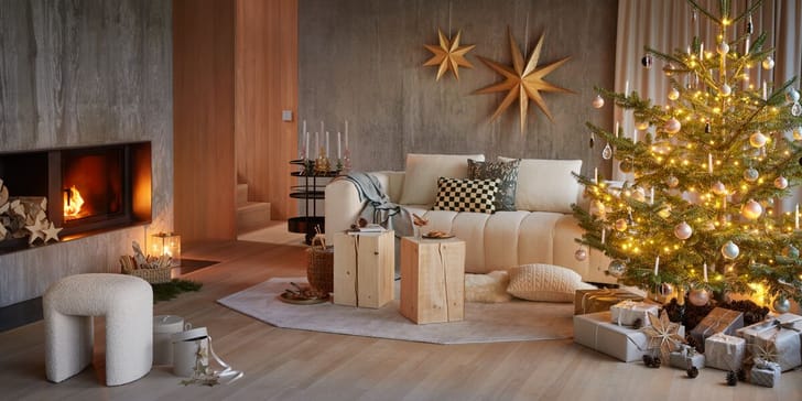 Gemütliches Wohnzimmer mit Weihnachtsbaum, Geschenken und Kaminfeuer.