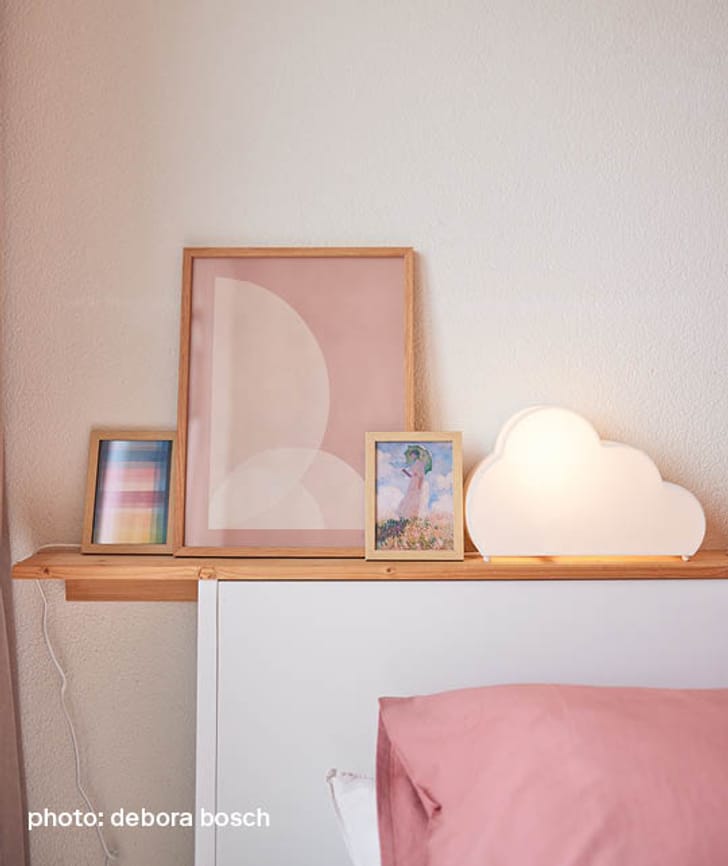 Une lampe en forme de nuage et des cadres photo sur une étagère au-dessus du lit.