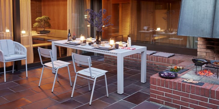 Table élégamment dressée sur une terrasse avec barbecue, idéale pour un dîner convivial en plein air.
