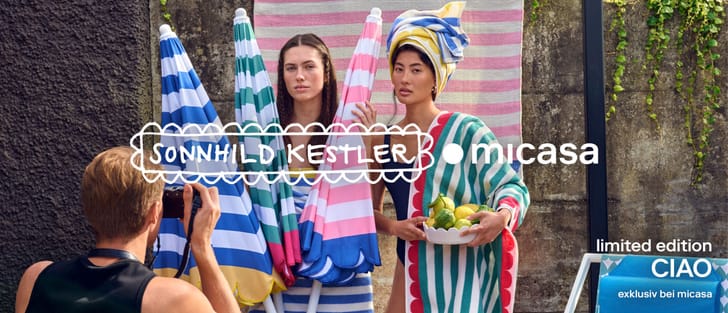 Zwei Personen in Badebekleidung halten farbenfrohe Strandtücher mit Mustern.