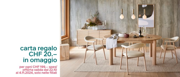 Sala da pranzo modernamente arredata con mobili in legno e parete in cemento, promozione di carta regalo sul lato sinistro.