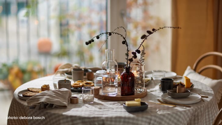 Une table joliment dressée avec vaisselle, verres et décorations pour un petit-déjeuner.